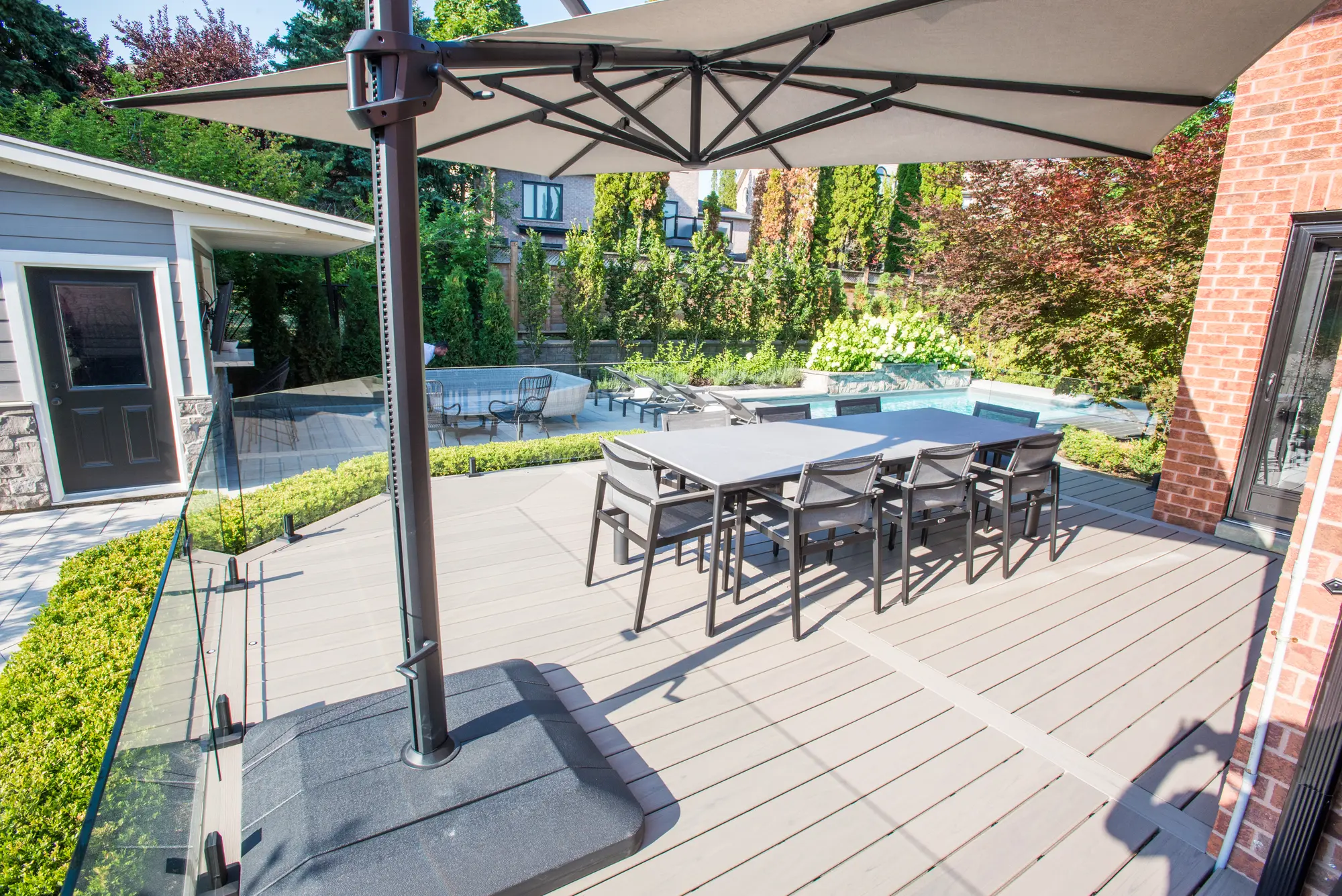 Composite deck dining area with glass railing beside a pool