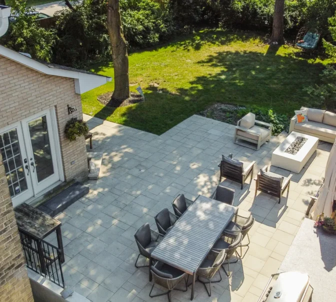 Elevated view of interlocking patio with lounge and dining areas beside the lawn