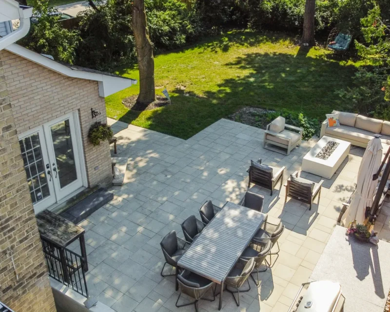 Elevated view of interlocking patio with lounge and dining areas beside the lawn