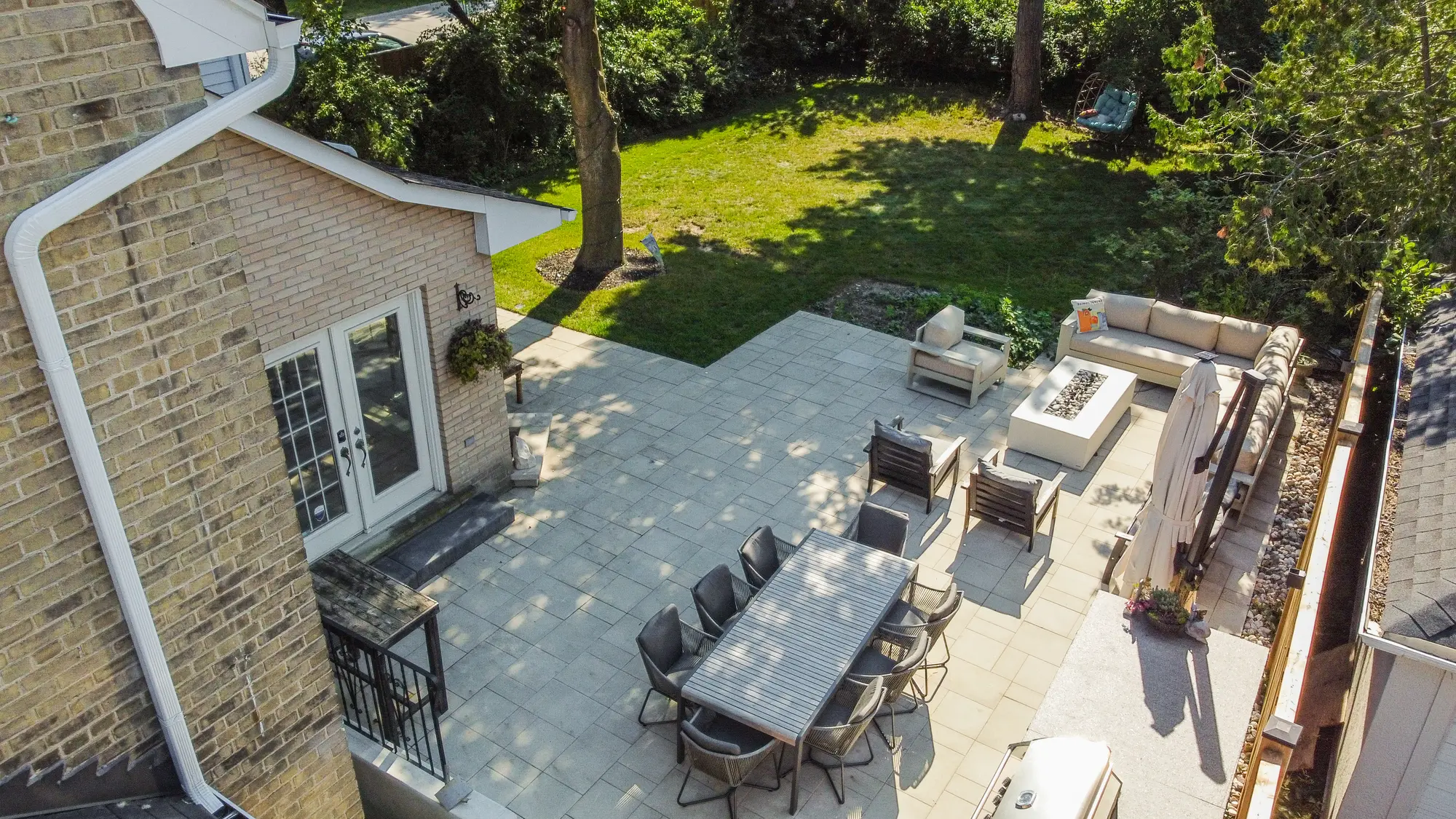 Elevated view of interlocking patio with lounge and dining areas beside the lawn