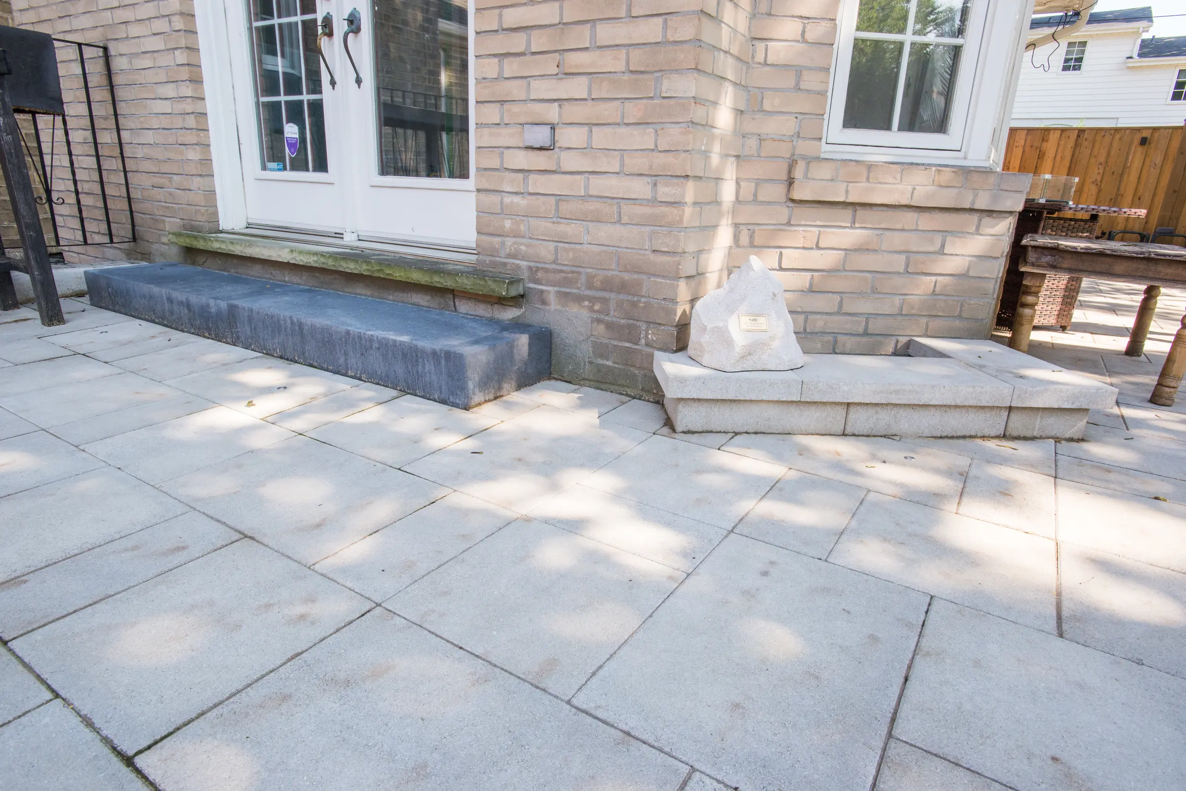 Memorial stone on a natural stone bench beside the interlocking patio