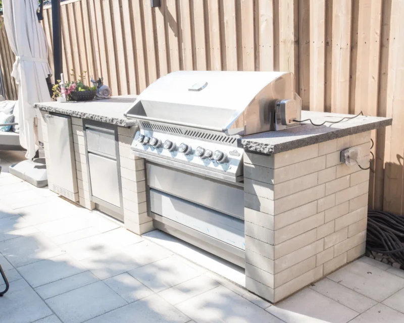 Outdoor kitchen with built-in grill and fridge on interlocking patio