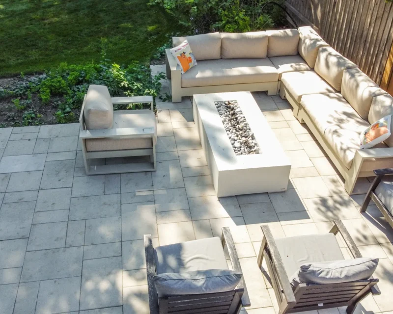 Patio sectional sofa around a fire pit table on interlocking stone