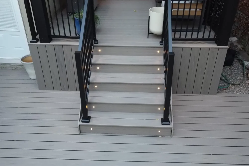 Lit Trex deck steps with black railing to the rear door