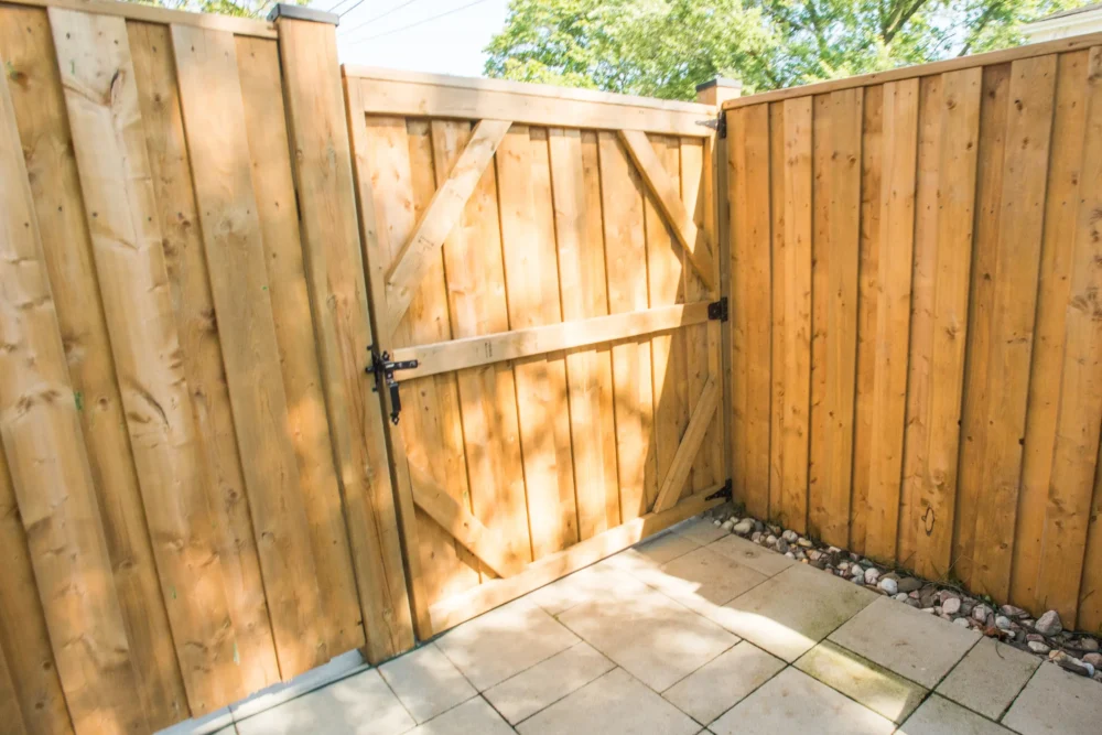 Wooden privacy fence gate opening onto interlocking stone