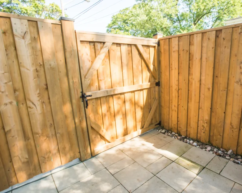 Wooden privacy fence gate opening onto interlocking stone